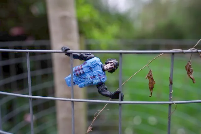 A toy figurine attached to a fence, marked as Unnamed by Apple because the face has no associated name.